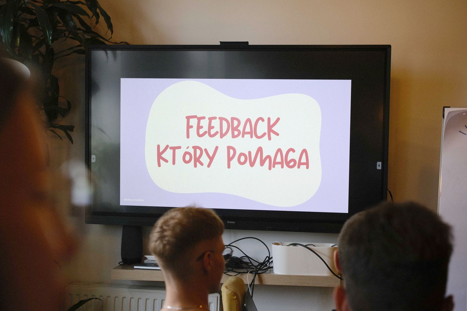 Ekran z tytułem warsztatu Feedback, który pomaga i uczestnicy na sali